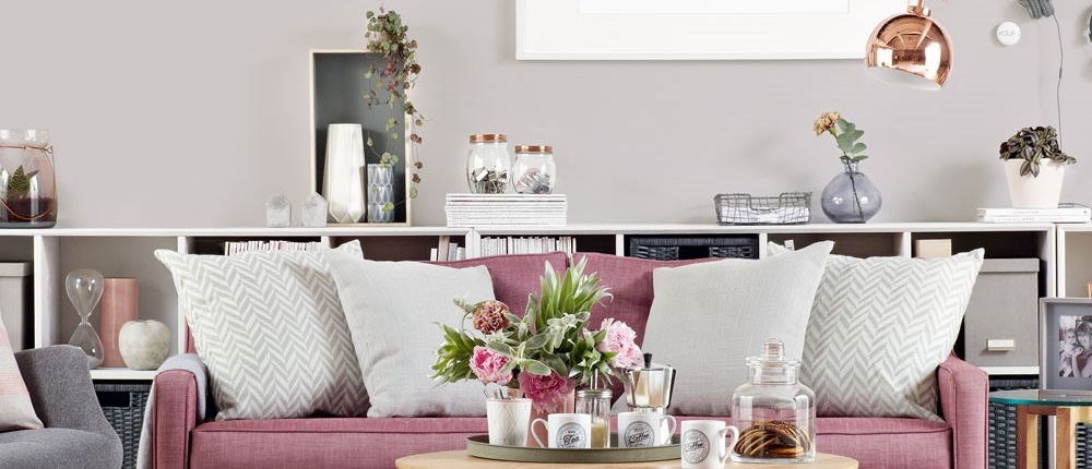 Grijze woonkamer met roze bankstel en koperkleurige accenten